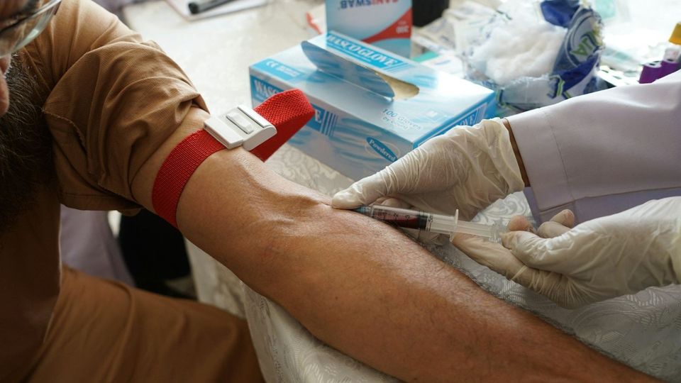 A gloved professional taking a blood sample from a person's arm