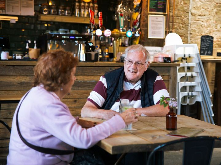Two people talking over drinks at a café table