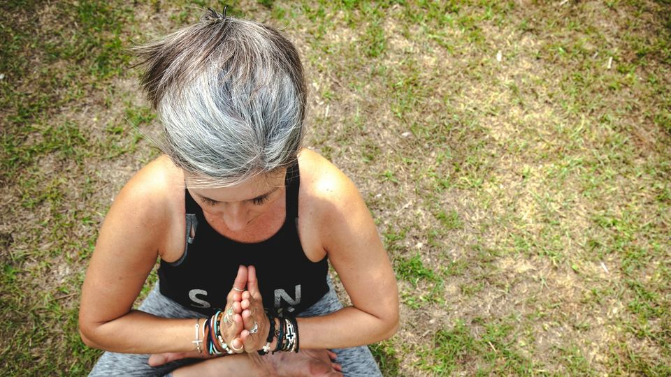 A woman sitting cross-legged on the grass, taking a quiet moment